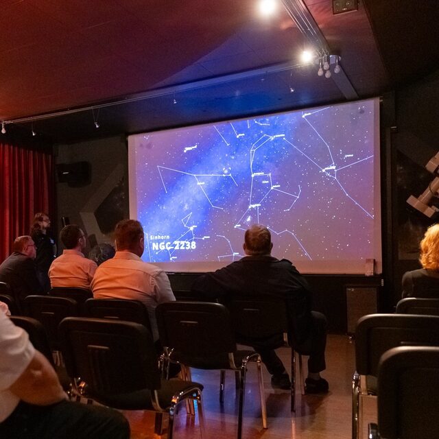 Das Publikum verfolgt eine Präsentation mit astronomischen Karten und Bildern.