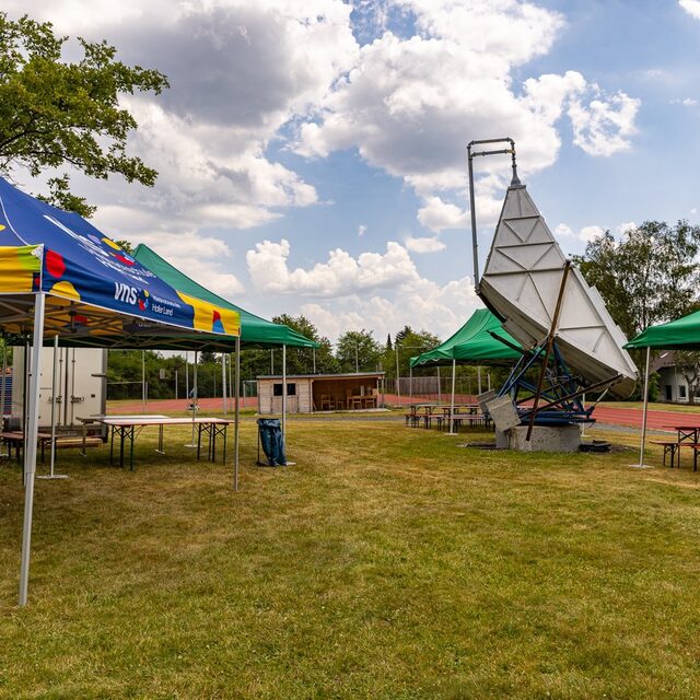 Festbereich mit Pavillons, Sitzbänken und Radioteleskop der Sternwarte.